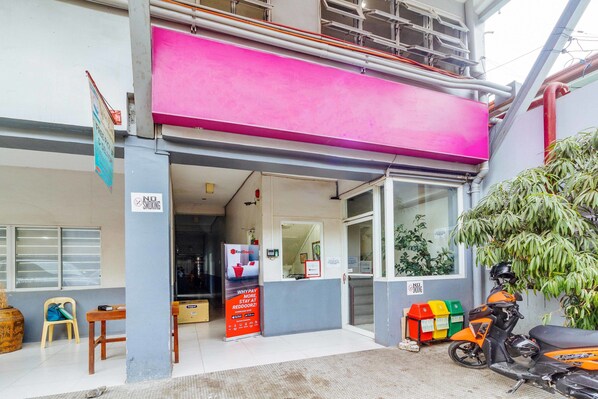 A building with a bright pink awning, a reception desk, and a motorcycle parked outside. - RedDoorz near Cebu Metropolitan Cathedral (Cebu City)