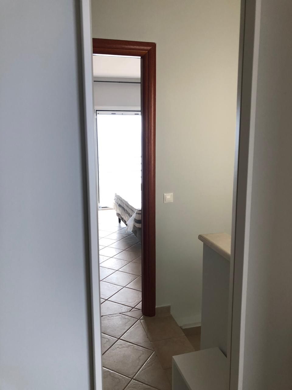 Een smalle gang met een houten deur die leidt naar een kamer met een bed.