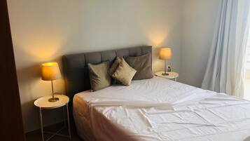 A neatly made bed with white bedding, two bedside lamps, and a headboard.
