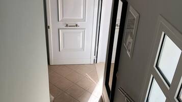 A hallway with a white door, a black-framed picture, and a window with a metal railing.