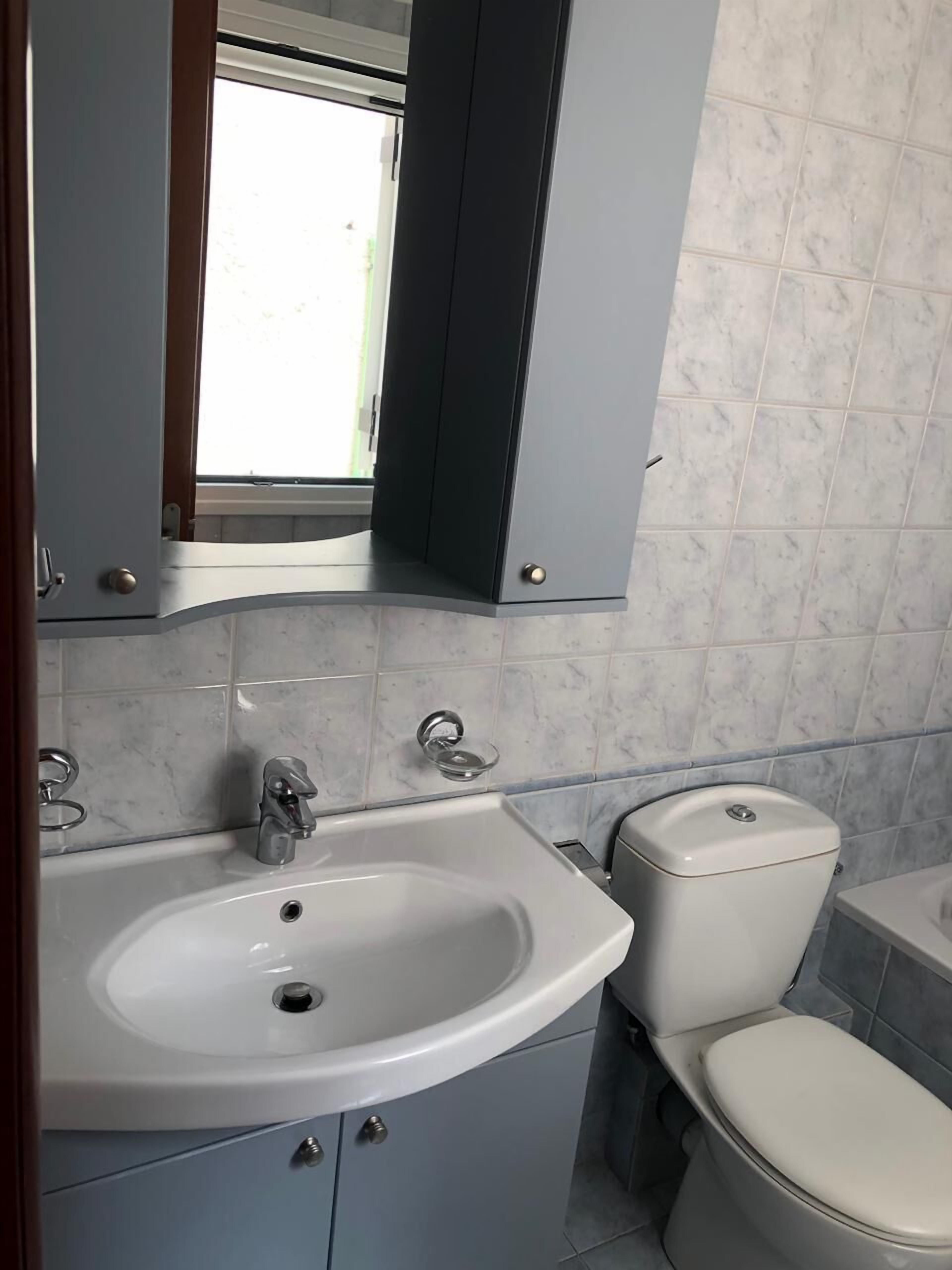 A bathroom with a white sink, a toilet, and a mirror above the sink.