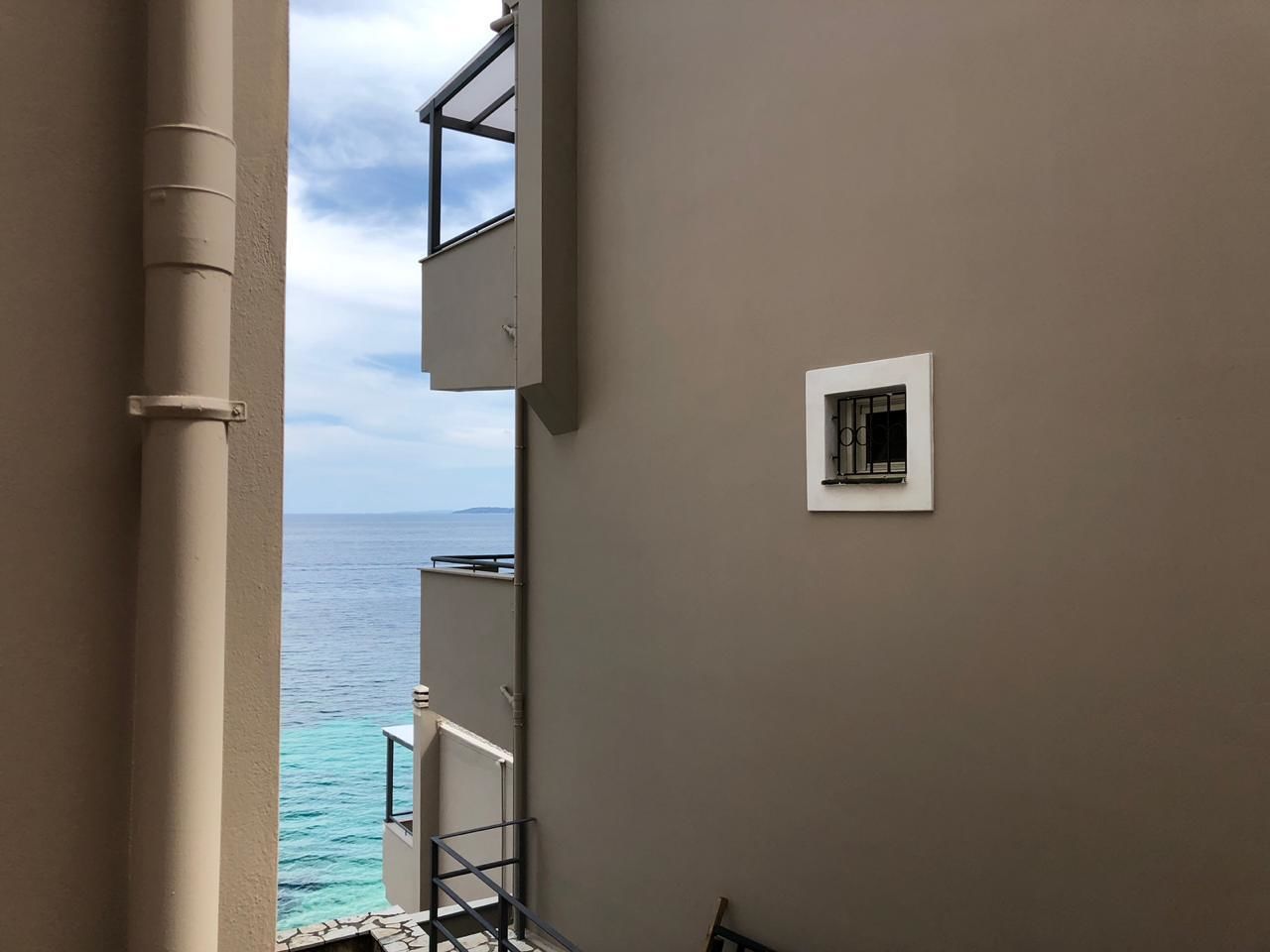 A narrow corridor with a view of the sea through a window.