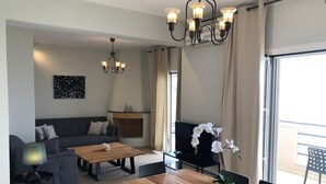A modern living room with a sofa, a wooden coffee table, a TV, and a fireplace. - Glyfa Beach Villas (Corfu)