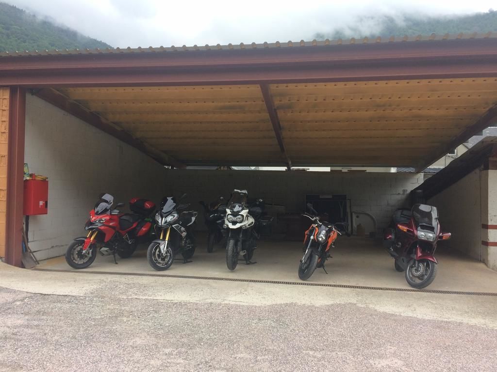 A covered parking area with five motorcycles parked in a row.