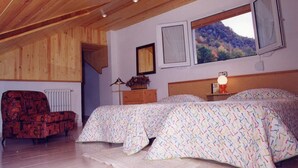 A bedroom with a wooden ceiling, two beds with patterned bedding, a red armchair, a radiator, and a window with a mountain view. - Hotel Talabart (Les)