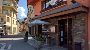 A restaurant with outdoor seating, stone walls, and a signboard. - Hotel Talabart (Les)