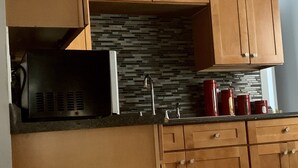 A kitchen with wooden cabinets, a microwave, a sink, and red kettles. - 2BR-Free Parking, 5Min to Providence, 10Min to Ma-I-95 (Pawtucket)
