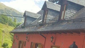 A red building with a sign that reads "HOTEL" and a chimney. - Hotel Colomers (Naut Aran)