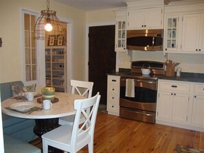 A kitchen with white cabinets, a stainless steel oven, and a dining table with chairs.