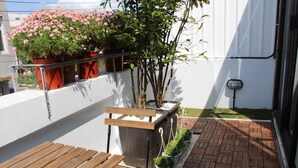 Eine Dachterrasse mit Holzbanken, Kübelpflanzen und einer weißen Wand.