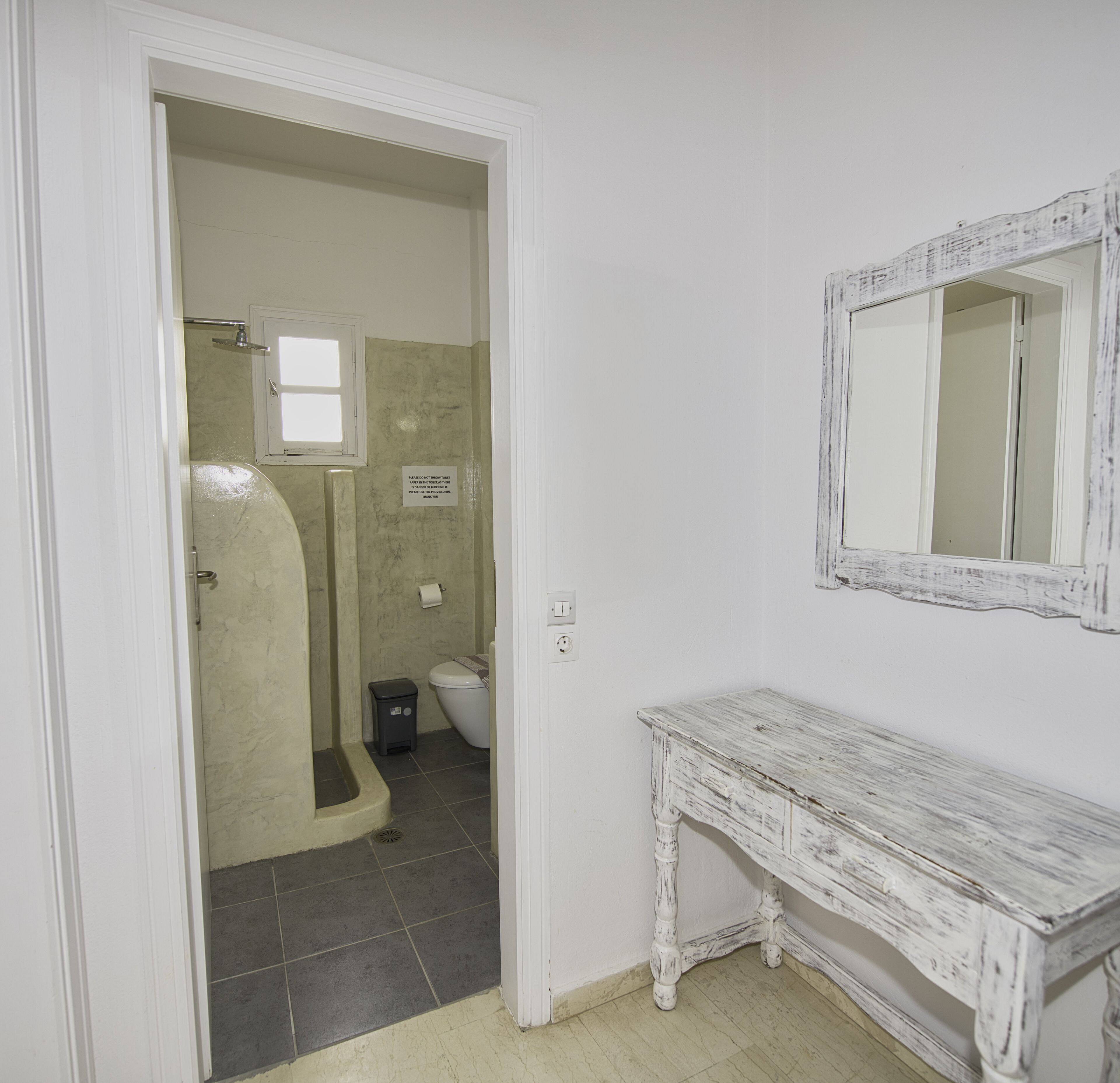 A bathroom with a shower, toilet, and a vanity with a mirror.