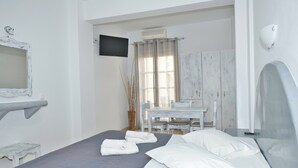 A bedroom with a bed, a desk, and a chair. - Ira Apartments (Santorini)
