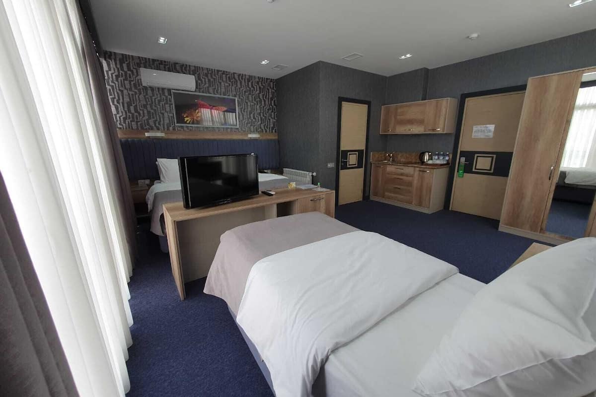 Een hotelkamer met twee bedden, een bureau met televisie, een kitchenette en een badkamer.