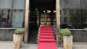 A hotel entrance with a red carpet leading to the door, a sign indicating it offers suites, a bakery, and a halal restaurant.