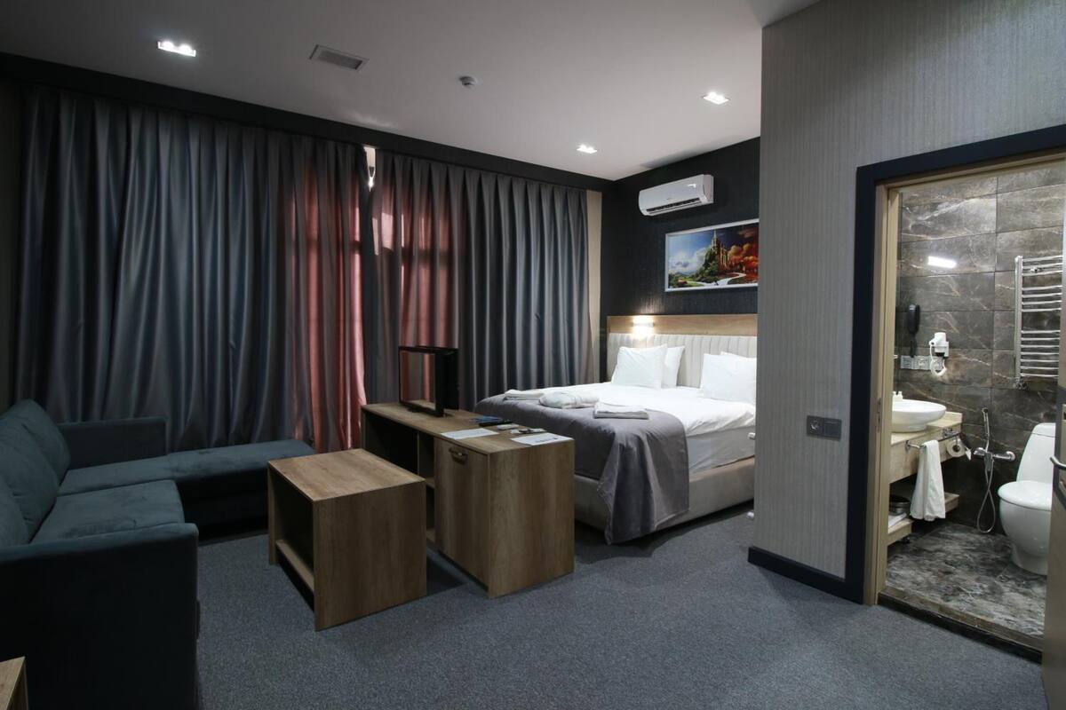Een moderne hotelkamer met een bed, een slaapbank, een bureau en een badkamer.