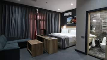 Una habitación de hotel moderna con cama, sofá, escritorio y baño.