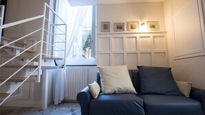 A modern living room with a dark blue sofa, a white radiator, and a white spiral staircase. - Villa Klaudia - charming house_ Ercolano (San Giorgio a Cremano)