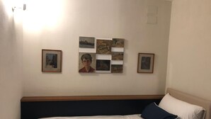 A hotel room with a bed, a headboard, and a wall with framed pictures. - Villa Klaudia - charming house_ Ercolano (San Giorgio a Cremano)