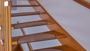 Een houten trap met een leuning en een muur met ingelijste foto's.
