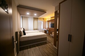 A hotel room with a large bed, a desk with a chair, a TV, and a wardrobe. - Cevik Palace Otel (Antalya)