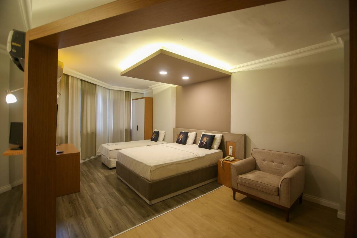 Habitación de hotel con dos camas, un sofá, un escritorio y un espejo.
