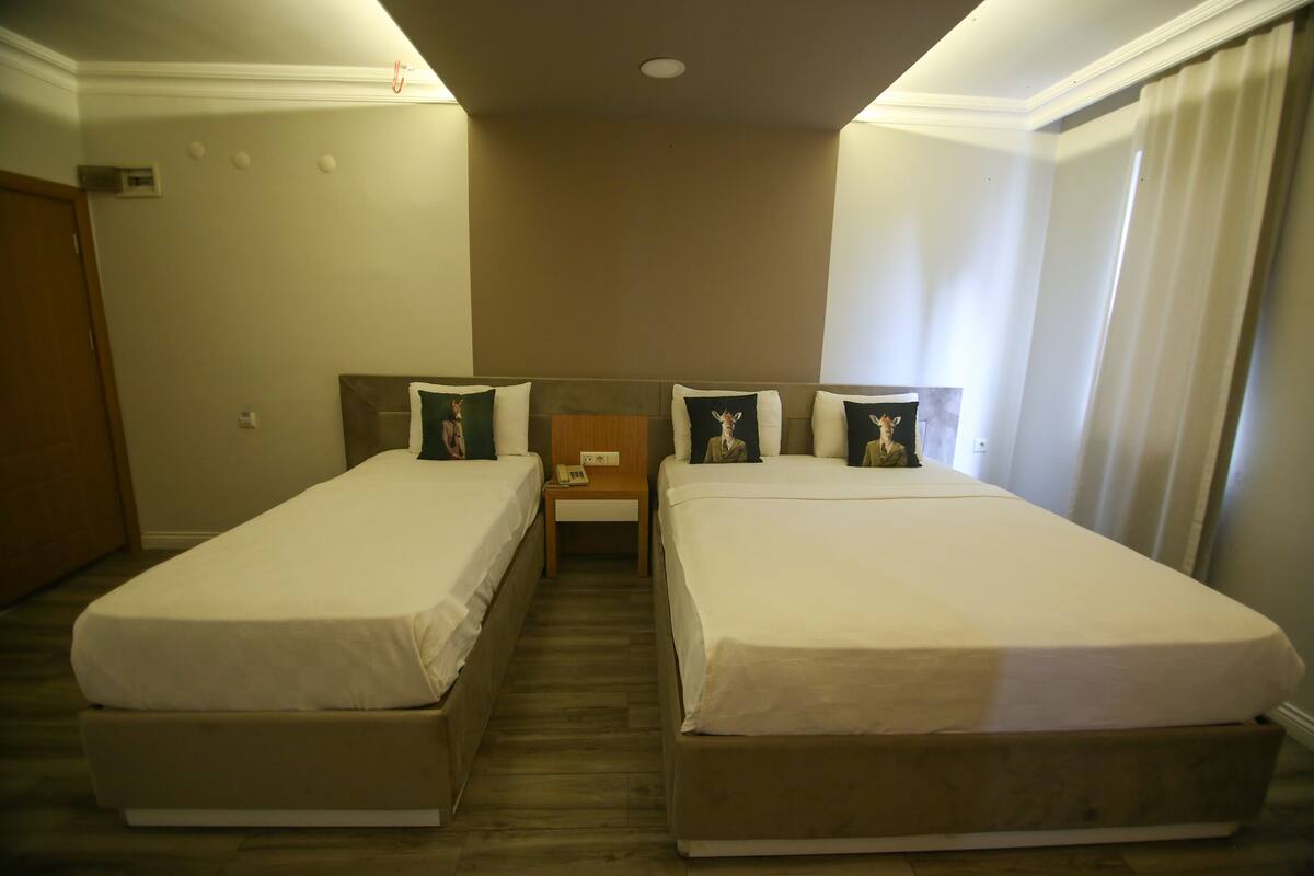 Una habitación de hotel con dos camas individuales, una mesita de noche de madera y una pequeña mesa.