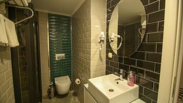 A bathroom with a glass sink, a mirror, a hairdryer, and a toilet.