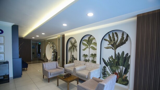 A modern lobby with a reception desk, seating area, and decorative plant wall. - Cevik Palace Otel (Antalya)
