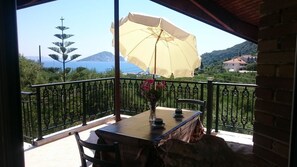 A balcony with a table, chairs, a yellow umbrella, and a vase of flowers. - Dakis Studios (Zakynthos)