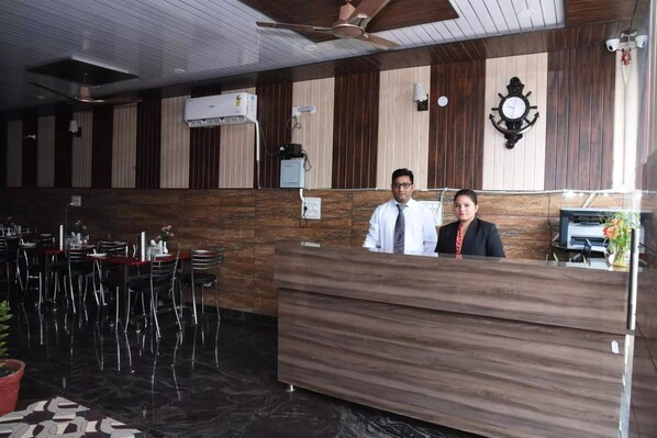 A reception area with a wooden reception desk, a clock on the wall, and a ceiling fan.