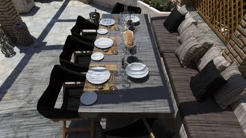 A dining area with a long table set for a meal, surrounded by cushioned seating and a wooden bench.