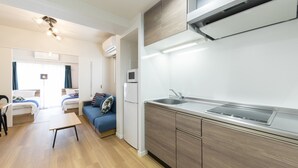 A compact kitchen with a built-in stove, a sink, and wooden cabinets. - SG Residence Inn Hakata (Fukuoka)