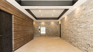 A hallway with a brick wall, a wooden panel wall, and a tiled floor. - SG Residence Inn Hakata (Fukuoka)