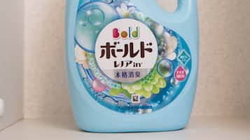 A bottle of laundry detergent with a blue cap and a label featuring floral and bubble designs.