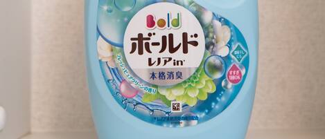 Une bouteille de lessive avec un bouchon bleu et une étiquette ornée de motifs floraux et de bulles.