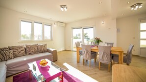 Ein modernes Wohnzimmer mit Sofa, Couchtisch und Essbereich mit Stühlen und Tisch.