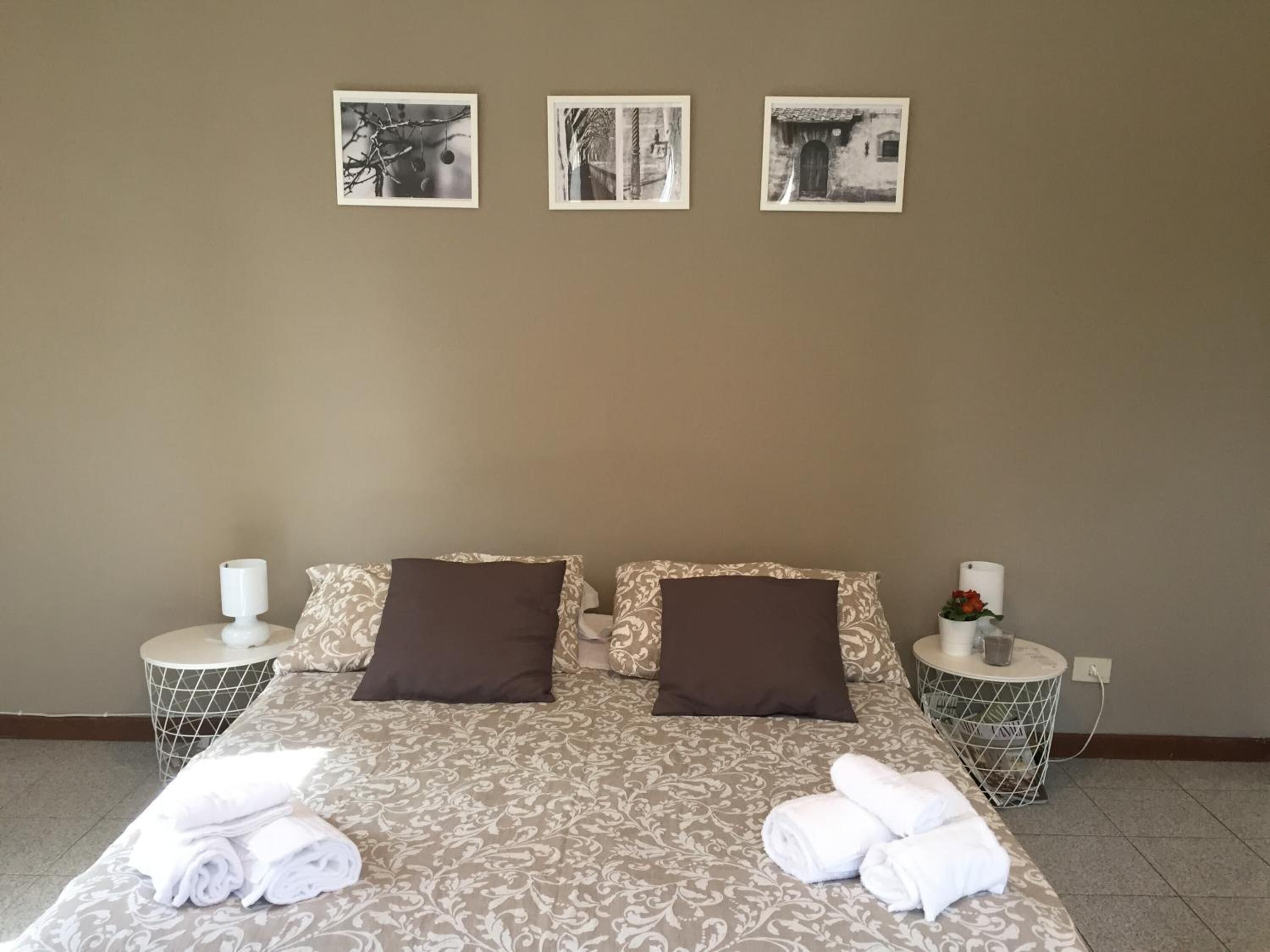 Una habitación de hotel con una cama, dos mesitas de noche y tres cuadros en la pared.