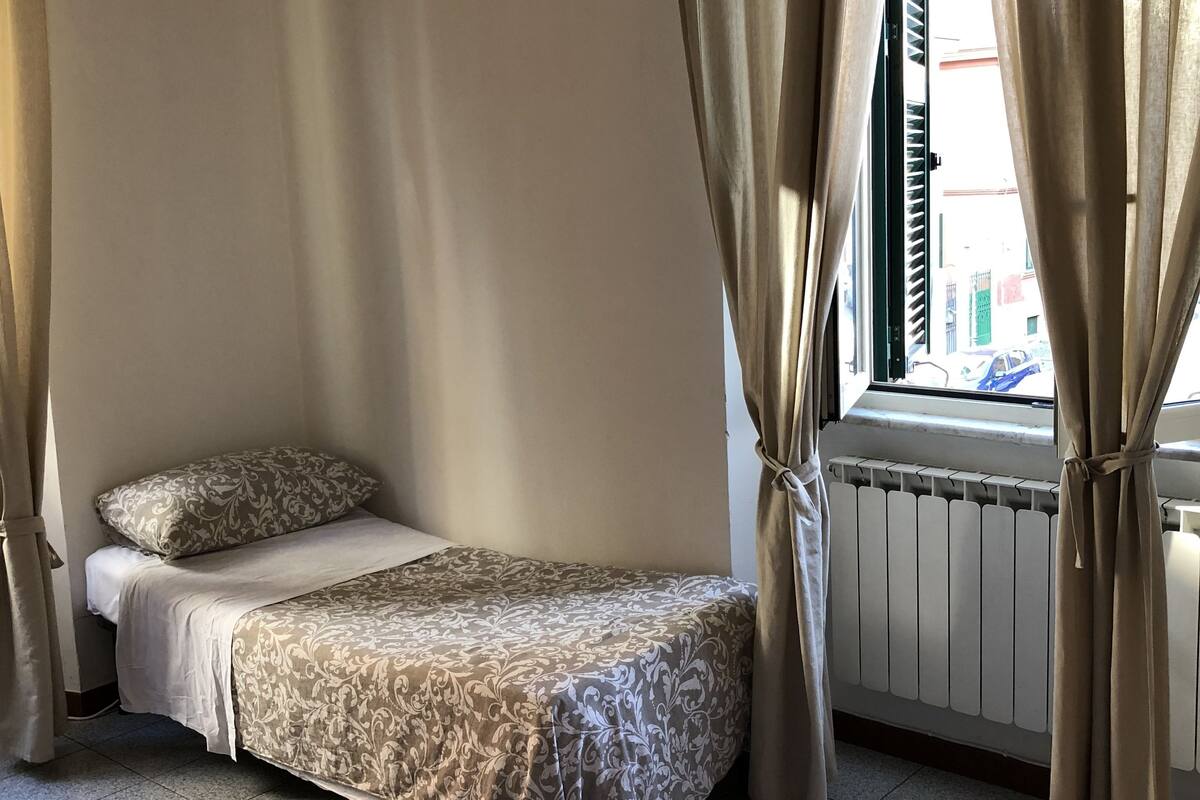 A small, neatly arranged bedroom with a bed, a radiator, and curtains.