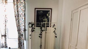 A living room with a sofa, a dining table with chairs, and a radiator with hanging vines. - Domus Santa Caterina (Rome)