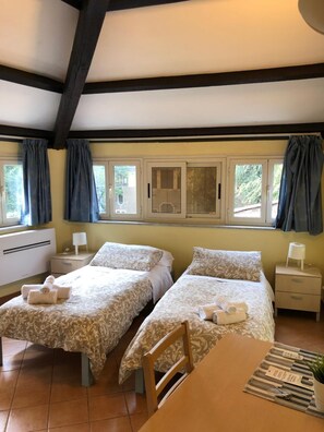 Une chambre avec deux lits, une table en bois et une fenêtre avec des rideaux.