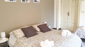 A hotel room with a large bed, two pillows, a bedside table with a lamp, and a small table with towels. - Domus Santa Caterina (Rome)