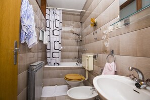 Een kleine badkamer met douche, toilet en wastafel.
