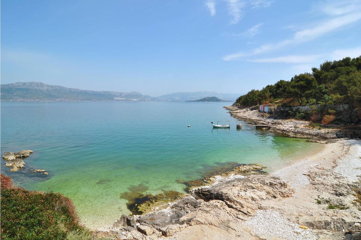 A coastal landscape with clear waters, rocky shore, and a boat.