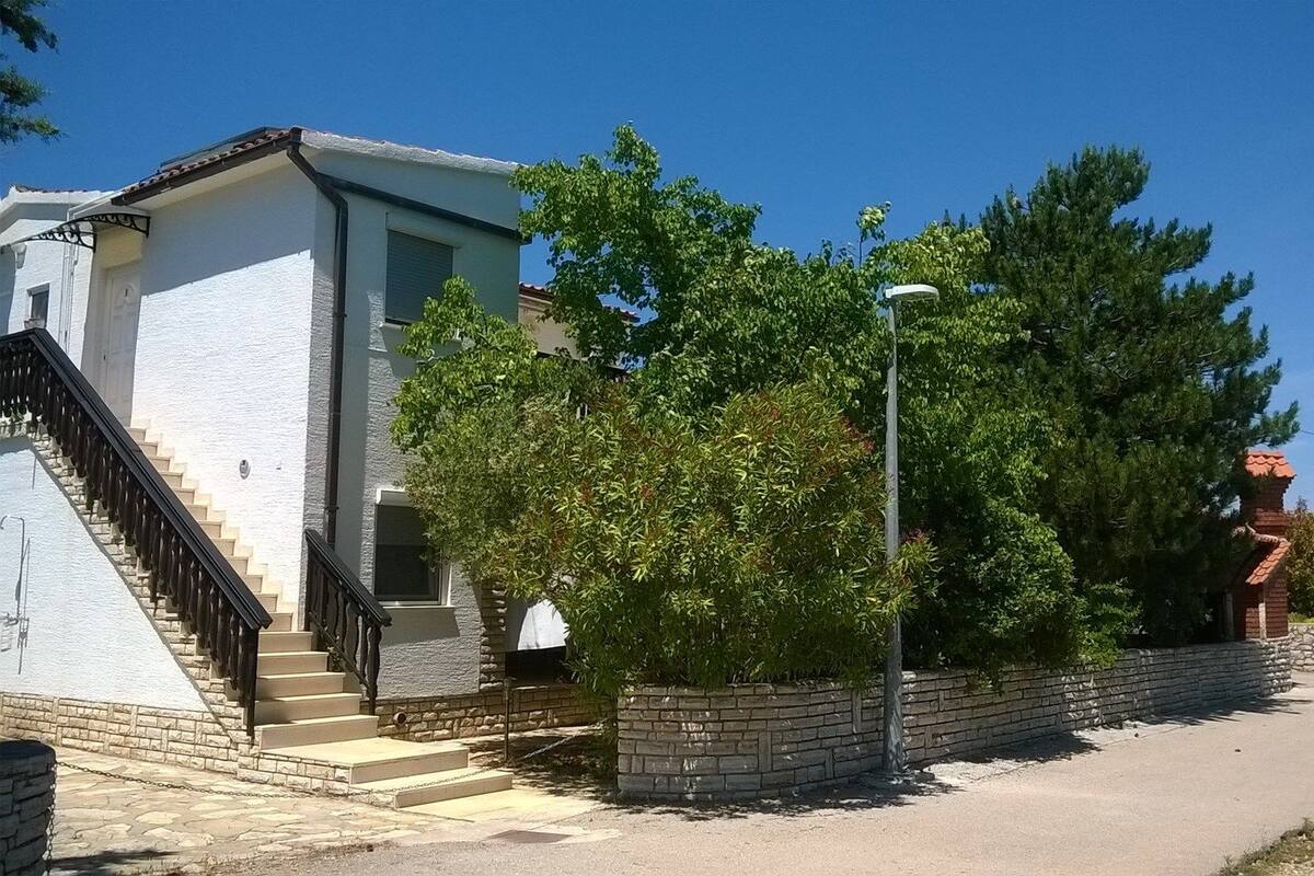 A residential building with a staircase leading to a door, a brick wall, and a street lamp.