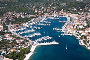 Vista aérea de un pueblo costero con un puerto deportivo lleno de barcos, rodeado de edificios residenciales.