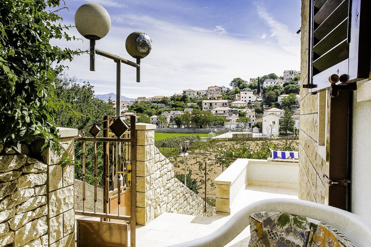 A stone staircase leading to a balcony with a view of a hillside town.