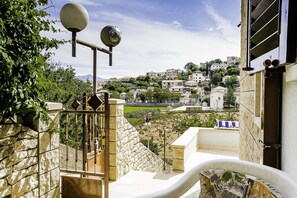 Un escalier en pierre mène à un balcon d’où l’on peut admirer une ville perchée sur une colline.