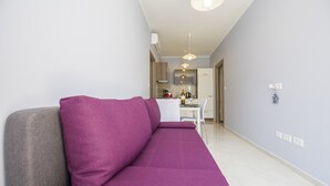 A modern living room with a purple sofa, a grey armchair, and a kitchen in the background. - Apartments Zazah (Liznjan)