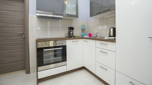 A compact kitchen with white cabinets, a built-in oven, and a coffee maker. - Apartments Zazah (Liznjan)