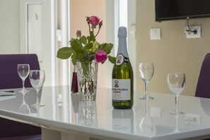 A table with a bottle of wine, a vase with flowers, and empty wine glasses. - Apartments Zazah (Liznjan)